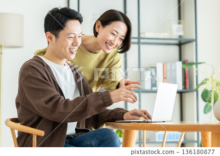 Middle-aged couple looking at a computer at home Middle-aged couple looking at a computer at home 136180877