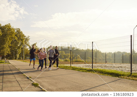 Group of adult runners jogging together in park on sunny day for fitness training outdoors Group of adult runners jogging together in park on sunny day for fitness training outdoors 136180923