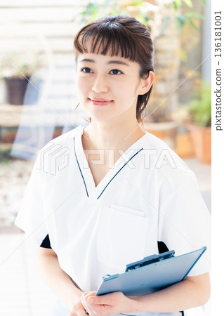 A female medical worker wearing a scrub and standing by the window A female medical worker wearing a scrub and standing by the window 136181001