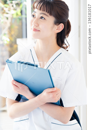A female medical worker wearing a scrub and standing by the window A female medical worker wearing a scrub and standing by the window 136181017