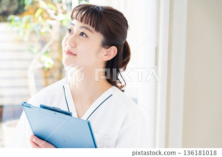 A female medical worker wearing a scrub and standing by the window A female medical worker wearing a scrub and standing by the window 136181018