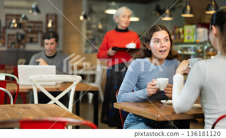 Two women talking over cup of coffee in cafe 136181120