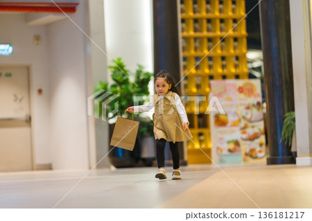 child girl walking with shopping bag in a department store 136181217