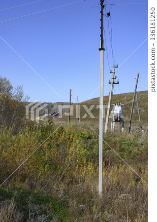 Transformer box, poles and electric wires on an overgrown meadow in the village in Siberia in autumn Transformer box, poles and electric wires on an overgrown meadow in the village in Siberia in autumn 136181250