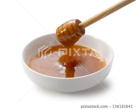 Manuka honey and honey dipper on white background, dripping honey in a white bowl Manuka honey and honey dipper on white background, dripping honey in a white bowl 136181641