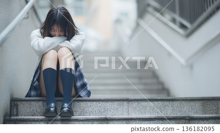 A Japanese female student crouches on the stairs, rejecting the outside world 136182095