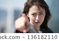 A Japanese woman looks straight at the camera and points her finger 136182110