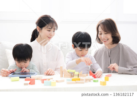 祖孫三代,祖母、母親和孩子麵帶笑容地玩著積木,這是一張父母與孩子幸福的合影,照片中還有兩個孩子(孫子)和兄弟姊妹。 祖孫三代,祖母、母親和孩子麵帶笑容地玩著積木,這是一張父母與孩子幸福的合影,照片中還有兩個孩子(孫子)和兄弟姊妹。 136182117