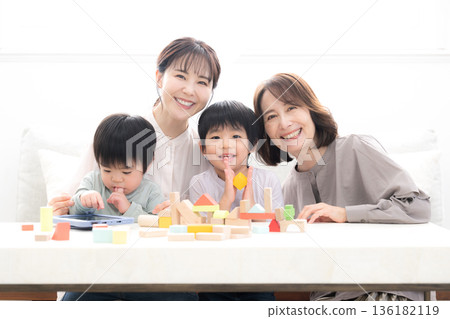祖孫三代，祖母、母親和孩子麵帶笑容地玩著積木，這是一張父母與孩子幸福的合影，照片中還有兩個孩子（孫子）和兄弟姊妹。 136182119