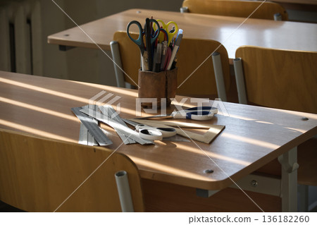 Classroom Desk With Stationery Under Natural Light in an Educational Setting 136182260