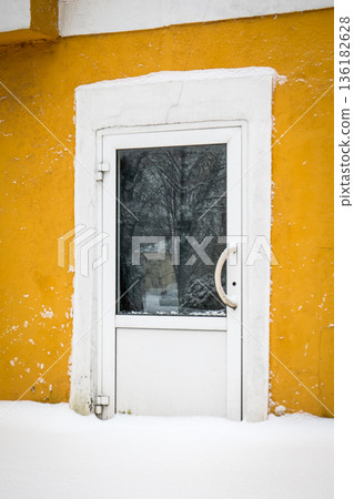 Snow Covered Basement Door On Yellow Residential Building Wall 136182628