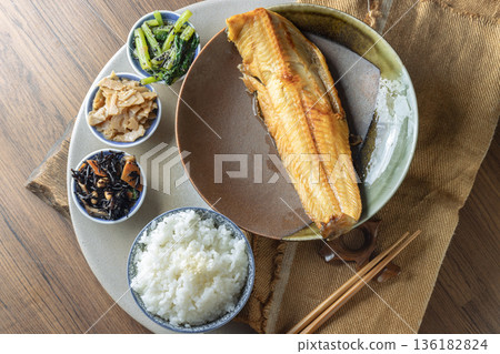 A traditional Japanese teishoku set meal features a large, golden-brown charcoal-grilled Atka mackerel, also known as Shima Hokke. A traditional Japanese teishoku set meal features a large, golden-brown charcoal-grilled Atka mackerel, also known as Shima Hokke. 136182824