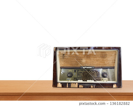 A vintage, retro-style radio sits on a wooden table against a white background. Front view. A vintage, retro-style radio sits on a wooden table against a white background. Front view. 136182882