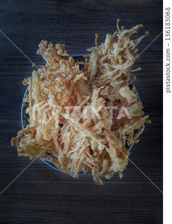 Crispy fried enoki, also known as deep-fried needle mushrooms, are coated with spiced flour and deep-fried to a golden-brown, crunchy texture; they are served in a blue and white patterned bowl Crispy fried enoki, also known as deep-fried needle mushrooms, are coated with spiced flour and deep-fried to a golden-brown, crunchy texture; they are served in a blue and white patterned bowl 136183068