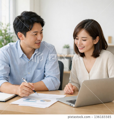 辦公室裡，男女職員面帶微笑，一邊開會一邊查看文件。商務形象 136183385