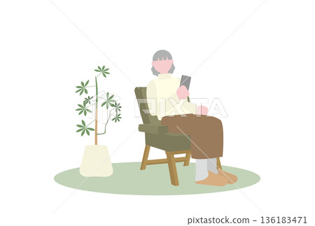 一位老年婦女獨自坐在沙發上，看著她的智慧型手機。 136183471