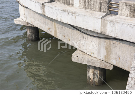 Concrete Pillars Structure Over The Sea, A striking photo of concrete pillars structure, tall gray rising from water in bright, perfect for coastal engineering or architecture documentary. 136183490