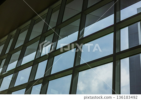 Glass Atrium Inside Building With Sky View, A bright photo of glass atrium building, towering transparent roof revealing clear clouds above interior, for modern architecture or urban documentary. Glass Atrium Inside Building With Sky View, A bright photo of glass atrium building, towering transparent roof revealing clear clouds above interior, for modern architecture or urban documentary. 136183492
