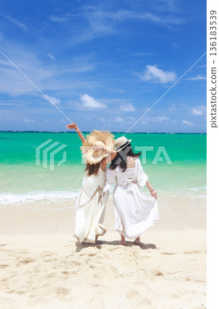 Back view of two women enjoying the sea in Miyakojima, Okinawa summer beach scenery Back view of two women enjoying the sea in Miyakojima, Okinawa summer beach scenery 136183539