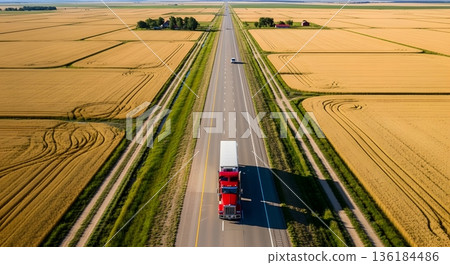 Aerial View Of Red Semi-Truck Driving Along Highway Through Golden Fields Under Sunny Sky 136184486