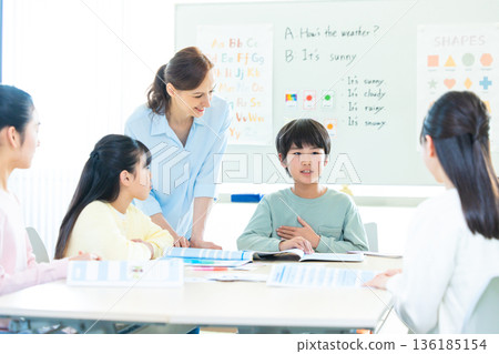 Education A child taking a lesson in an English conversation class and a native teacher Education A child taking a lesson in an English conversation class and a native teacher 136185154