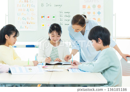 Education A child taking a lesson in an English conversation class and a native teacher Education A child taking a lesson in an English conversation class and a native teacher 136185186