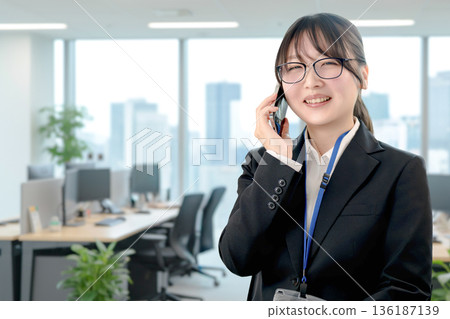 一位面帶微笑的漂亮女商人正在打電話。 一位面帶微笑的漂亮女商人正在打電話。 136187139