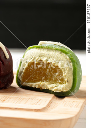 Sweet green dessert with creamy filling and fruit center on a wooden board during afternoon snack Sweet green dessert with creamy filling and fruit center on a wooden board during afternoon snack 136187367