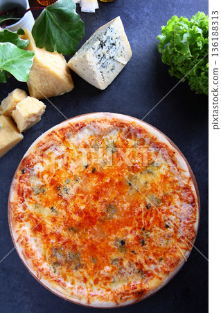 Classic Italian pizza with four cheeses. Slices of cheese are next to each other on the table. Cheese with mold. Top view. Black background. 136188313