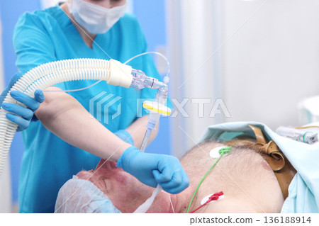 An elderly man is injected with an endotracheal tube. Tracheal intubation. Anesthesia before surgery. Modern medicine. Preparation for operation. 136188914