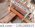 A machine for sawing wood. The edge of the wooden board is cut on the machine. Laser marking of wood. The woodworking industry. Wood processing at a sawmill. 136188915