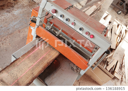 A machine for sawing wood. The edge of the wooden board is cut on the machine. Laser marking of wood. The woodworking industry. Wood processing at a sawmill. 136188915