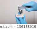Ceramic and composite veneers. A dental technician makes the measurement of the veneers. Hands in protective gloves. The concept of beauty and health. Copy space. Close-up. 136188916