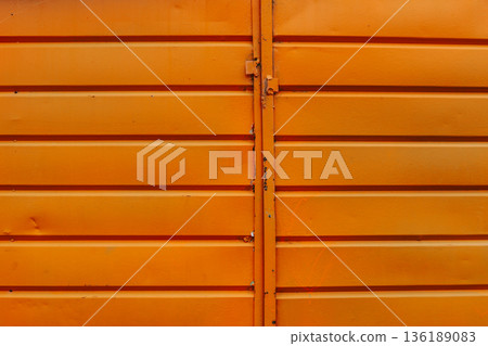 Cracked and rusty orange metal sheet texture close-up 136189083