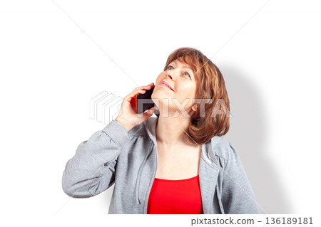 Happy woman talking on smartphone and looking up dreamily 136189181