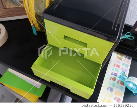Plastic green storage box with pull-out drawers for office supplies. Close-up of the layout. Organizing space in a room. Storage of items, office supplies. Education and materials, layout. Plastic green storage box with pull-out drawers for office supplies. Close-up of the layout. Organizing space in a room. Storage of items, office supplies. Education and materials, layout. 136189253