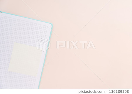 Grid notebook corner with sticky note and copy space, soft pastel background 136189308