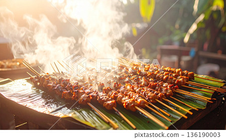 Grilled Chicken Satay Skewers on Banana Leaf with Morning Sunlight and Steam Grilled Chicken Satay Skewers on Banana Leaf with Morning Sunlight and Steam 136190003