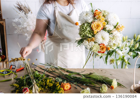 Creative entrepreneur holds lush flower bouquet in bright florist studio. Women in business, boutique owner, small business growth. 136190084