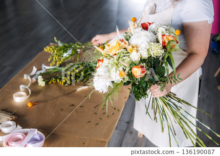 Florist demonstrates bouquet assembly during botanical art education session. Community workshop, florist teaching, experiential marketing. 136190087