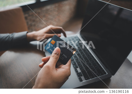 Sign of a new era, this man hand pose and gesture closeup shows him paying with a credit card and laptop, an important sign of secure online shopping and e-commerce activity 136190116