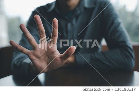 Close-up of an open hand reaching out, fingers extended towards the camera, with a blurry background of a person in a blue shirt. Close-up of an open hand reaching out, fingers extended towards the camera, with a blurry background of a person in a blue shirt. 136190117