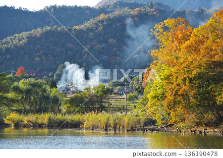 京都嵯峨野的秋景:田野焚燒產生的煙霧繚繞著被秋葉染成顏色的廣澤池。 京都嵯峨野的秋景:田野焚燒產生的煙霧繚繞著被秋葉染成顏色的廣澤池。 136190478