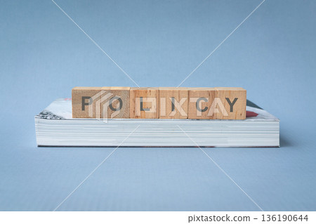Policy on wood blocks on top of a book. Policy on wood blocks on top of a book. 136190644