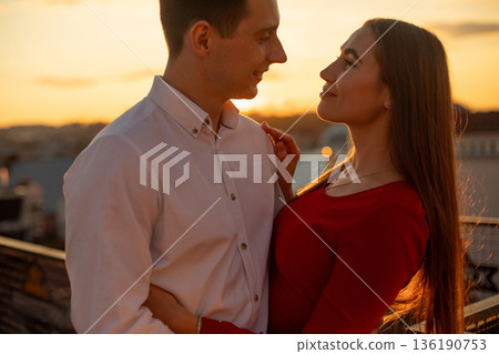Couple enjoys sunset while embracing on rooftop in city Couple enjoys sunset while embracing on rooftop in city 136190753