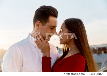 Couple sharing a moment during sunset in an outdoor setting with a city skyline in the background Couple sharing a moment during sunset in an outdoor setting with a city skyline in the background 136190820