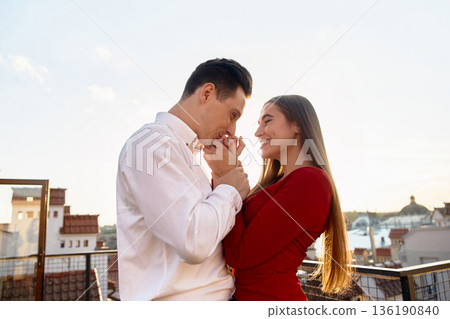 Couple shares a moment on rooftop during sunset overlooking the city skyline 136190840