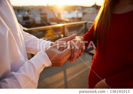 Couple exchanges rings during sunset on a rooftop in an urban area 136191015