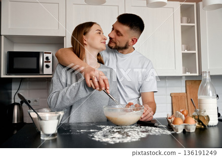 Couple Enjoys Cooking Together in a Cozy Kitchen While Mixing Ingredients for a Baking Recipe With Love and Joy in the Air Couple Enjoys Cooking Together in a Cozy Kitchen While Mixing Ingredients for a Baking Recipe With Love and Joy in the Air 136191249