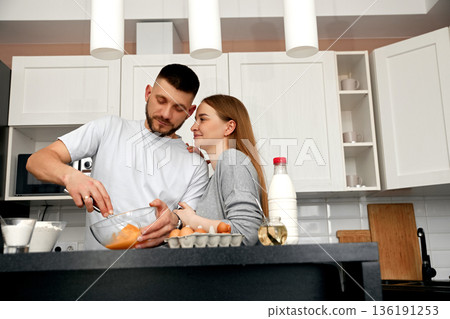 Couple Cooking Together in a Modern Kitchen While Mixing Eggs in a Bowl and Enjoying Each Other's Company During a Cozy Evening Couple Cooking Together in a Modern Kitchen While Mixing Eggs in a Bowl and Enjoying Each Other's Company During a Cozy Evening 136191253